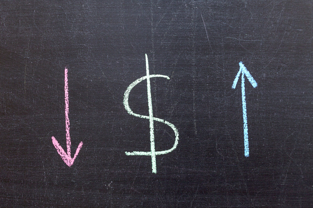 Chalkboard drawing with a dollar sign in the center, a red arrow pointing downward on the left, and a blue arrow pointing upward on the right, symbolizing financial changes or market fluctuations.